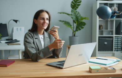 lady holding phone while working on a laptop
